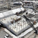 Aerial view of the Bull Run filtration facility under construction with concrete walls, formwork, and a crawler crane, Oregon