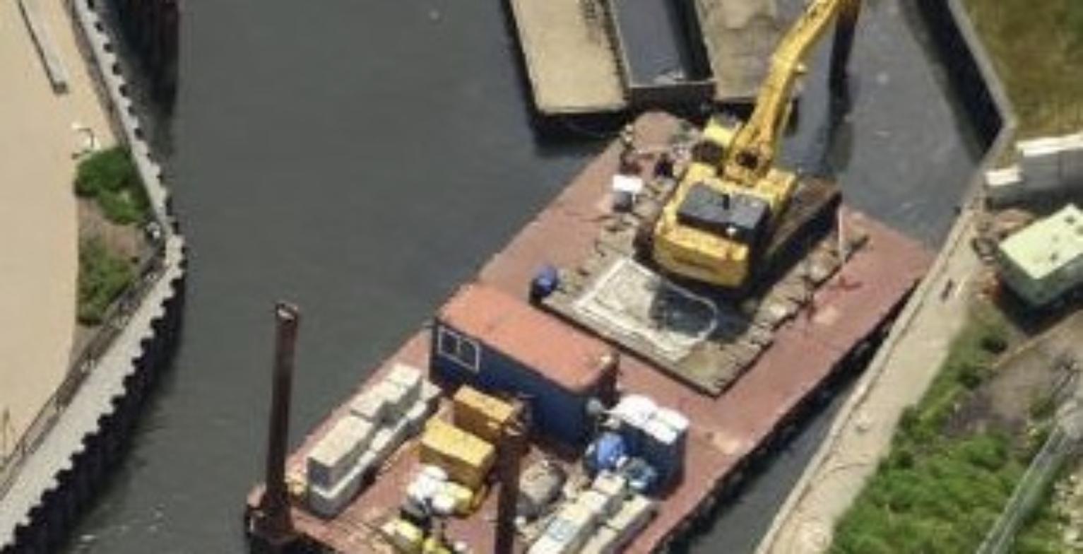 Excavator mounted on a barge dredging contaminated sediment from the Gowanus Canal in Brooklyn, New York