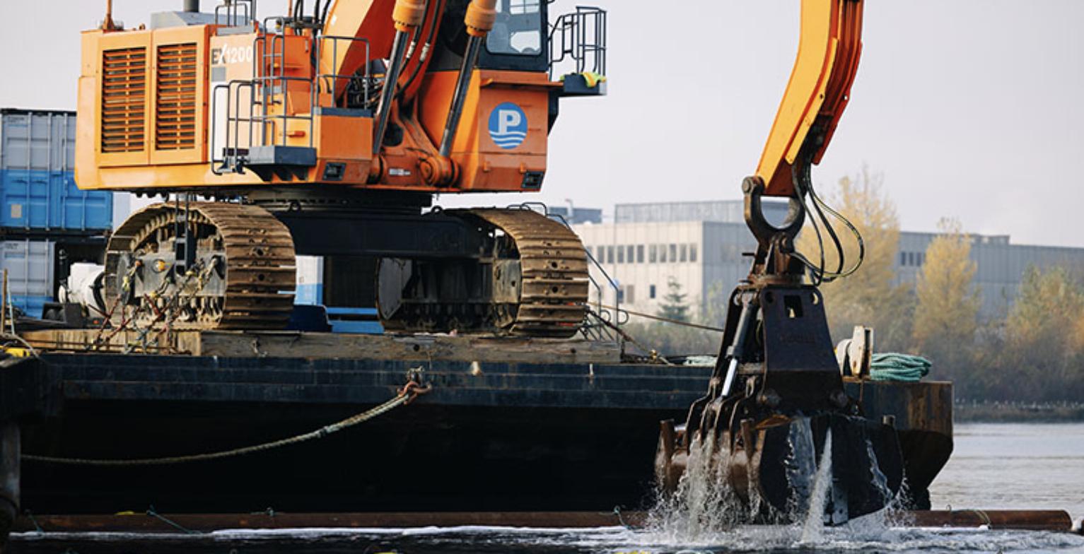 Excavator on a barge removing contaminated sediment from the Lower Duwamish Waterway in Seattle, Washington